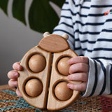 Bajo natural wooden ladybird teether  in a child's hands in the Babipur playroom.