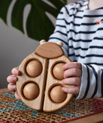 Bajo natural wooden ladybird teether  in a child's hands in the Babipur playroom.