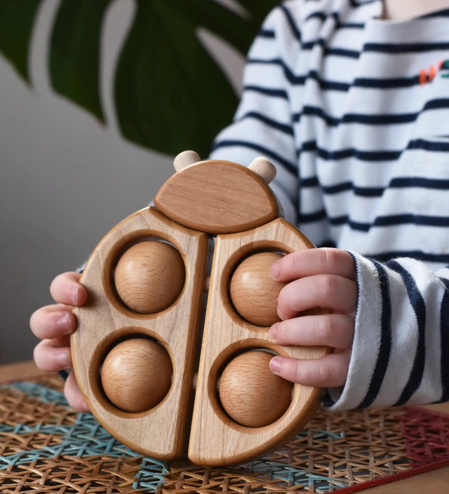 Bajo natural wooden ladybird teether  in a child's hands in the Babipur playroom.