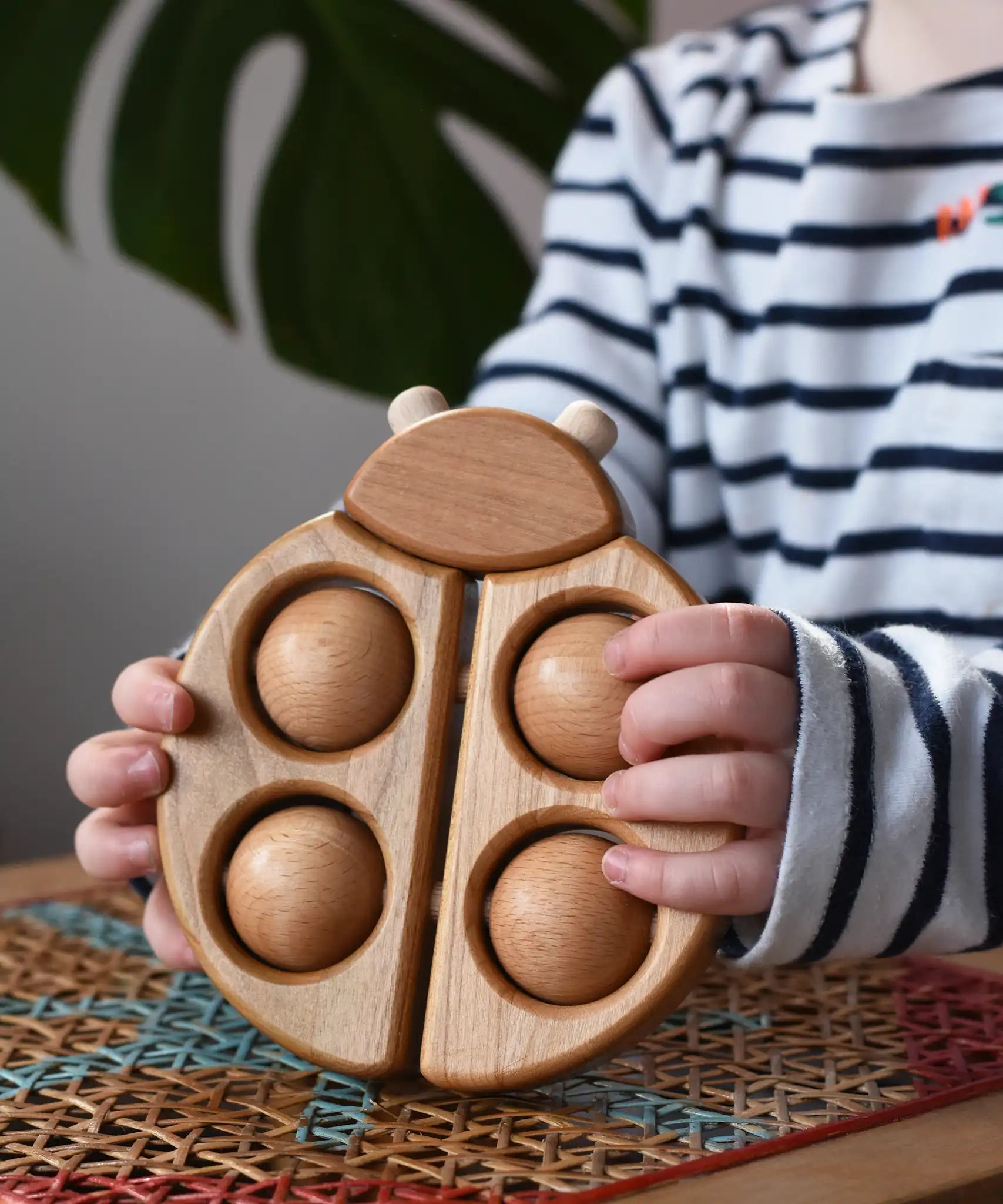 Bajo natural wooden ladybird teether  in a child's hands in the Babipur playroom.