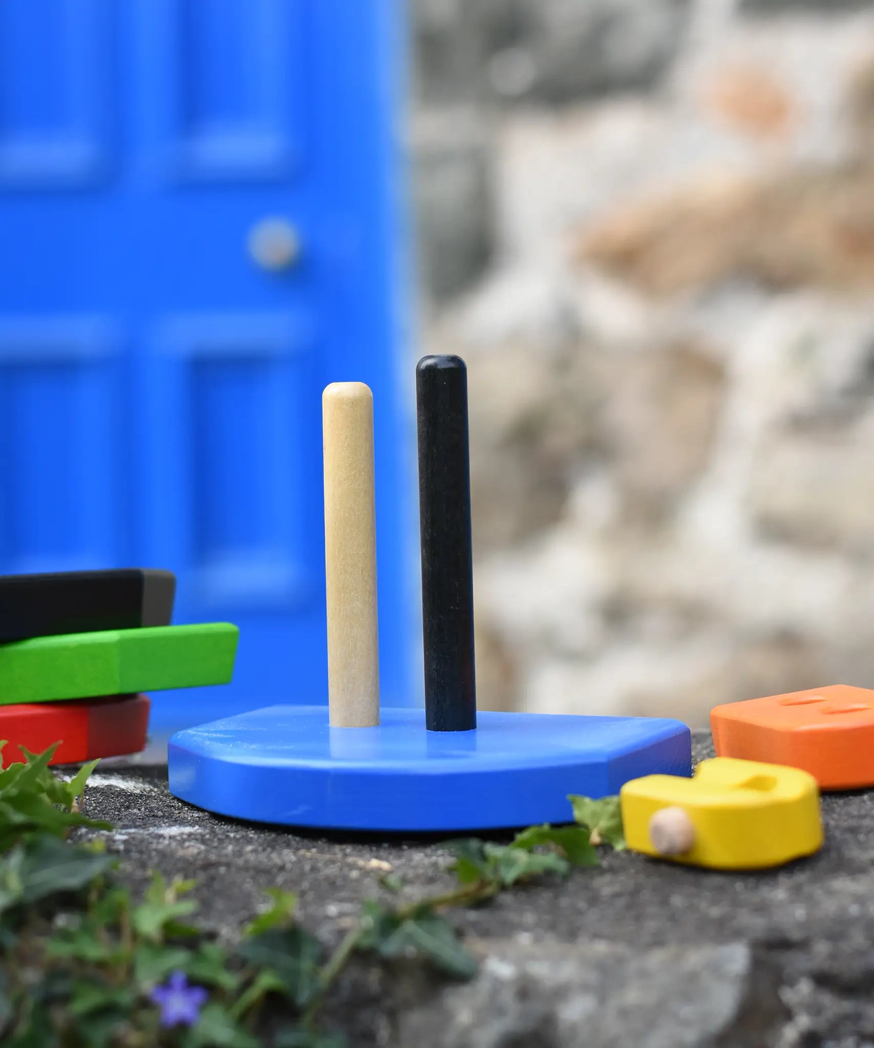 Base of the  Bajo nemo boat stacker toy placed on a stone wall with the pieces placed besides it.
