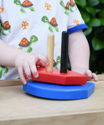 Child playing with the Bajo nemo boat stacker toy placing the red piece on the poles on the base.