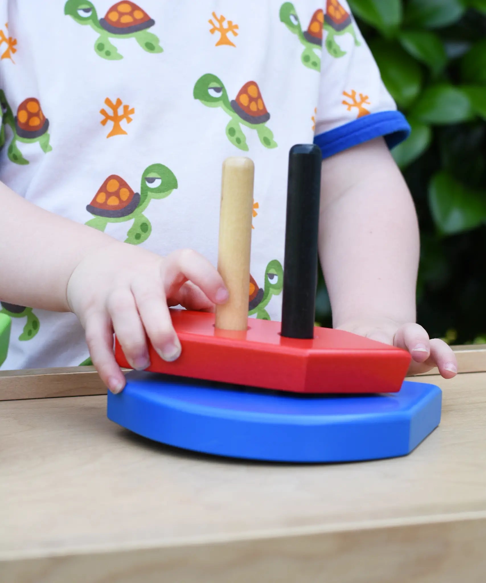 Child playing with the Bajo nemo boat stacker toy placing the red piece on the poles on the base.