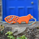 Bajo orange lacing fox wooden toy placed on a stone wall. 