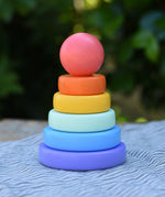 Bajo pastel stacking rings wooden toy. Purple base with pole, blue, green, yellow and orange rings with a pink red all pieces on top.