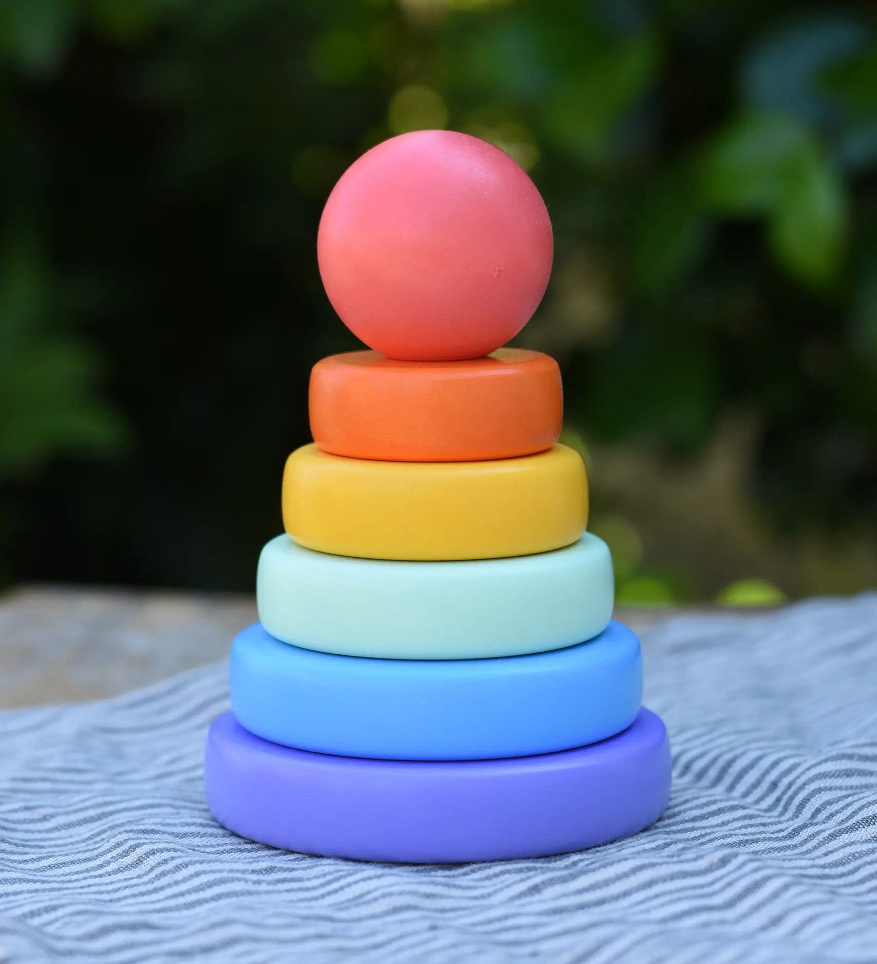Bajo pastel stacking rings wooden toy. Purple base with pole, blue, green, yellow and orange rings with a pink red all pieces on top.