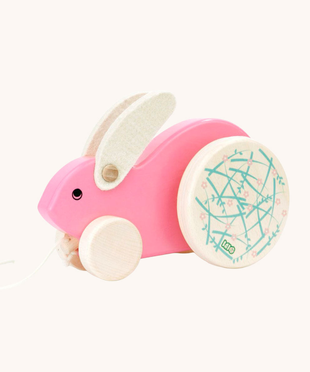 A pink Bajo Big Rabbit toy. This pull along wooden toy has small wheels at the front and large decorated wheels at the back. The rabbit makes a jumping motion as it is being pulled along. We have a wide range of Bajo wooden toys available here at Babipur. 
