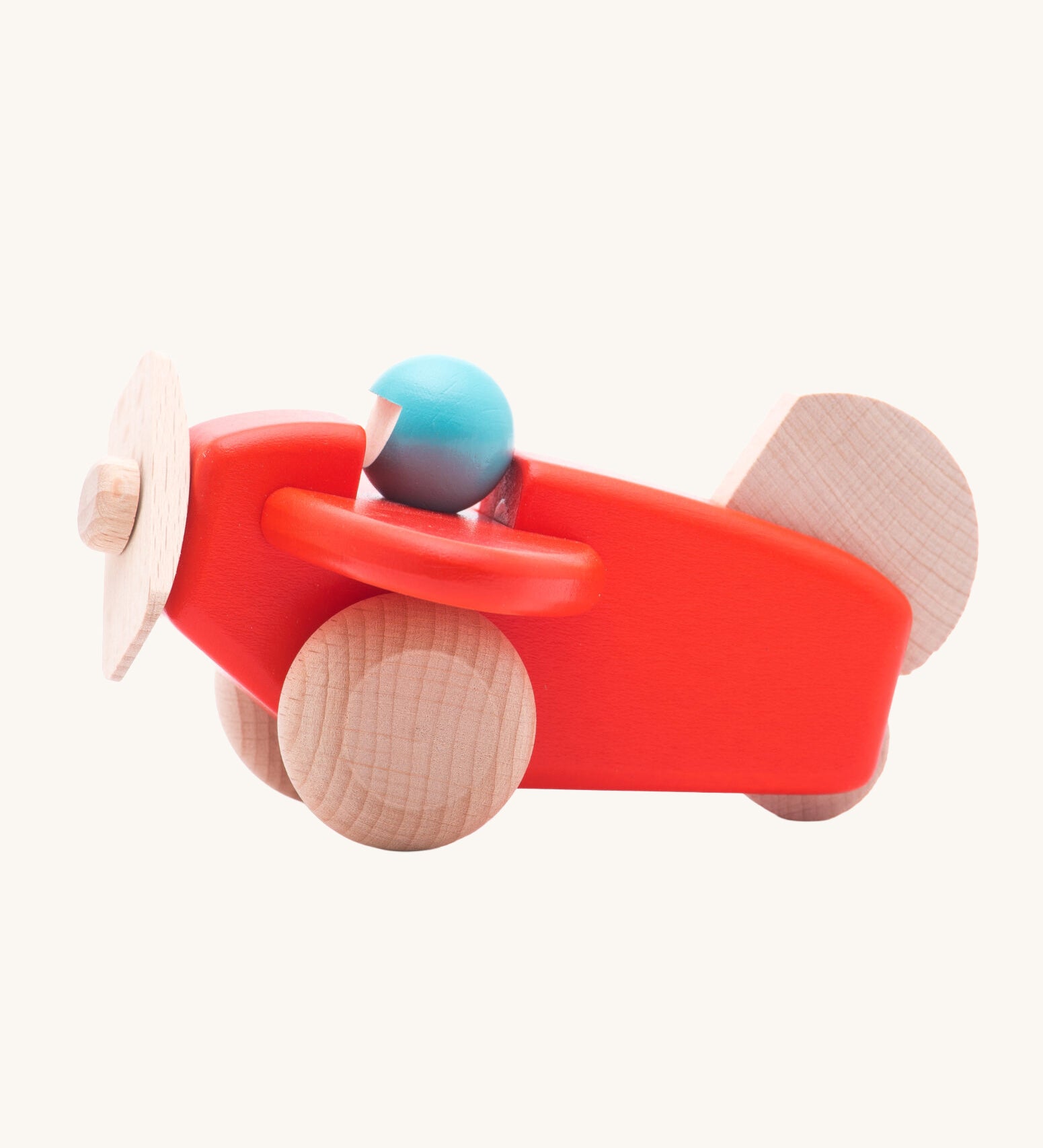 A Bajo coral wooden plane toy with pilot. The coral red coloured plane has natural wheels, propeller and tail and a blue coloured pilot. This plane is part of a wide range of Bajo wooden toy vehicles available at Babipur.