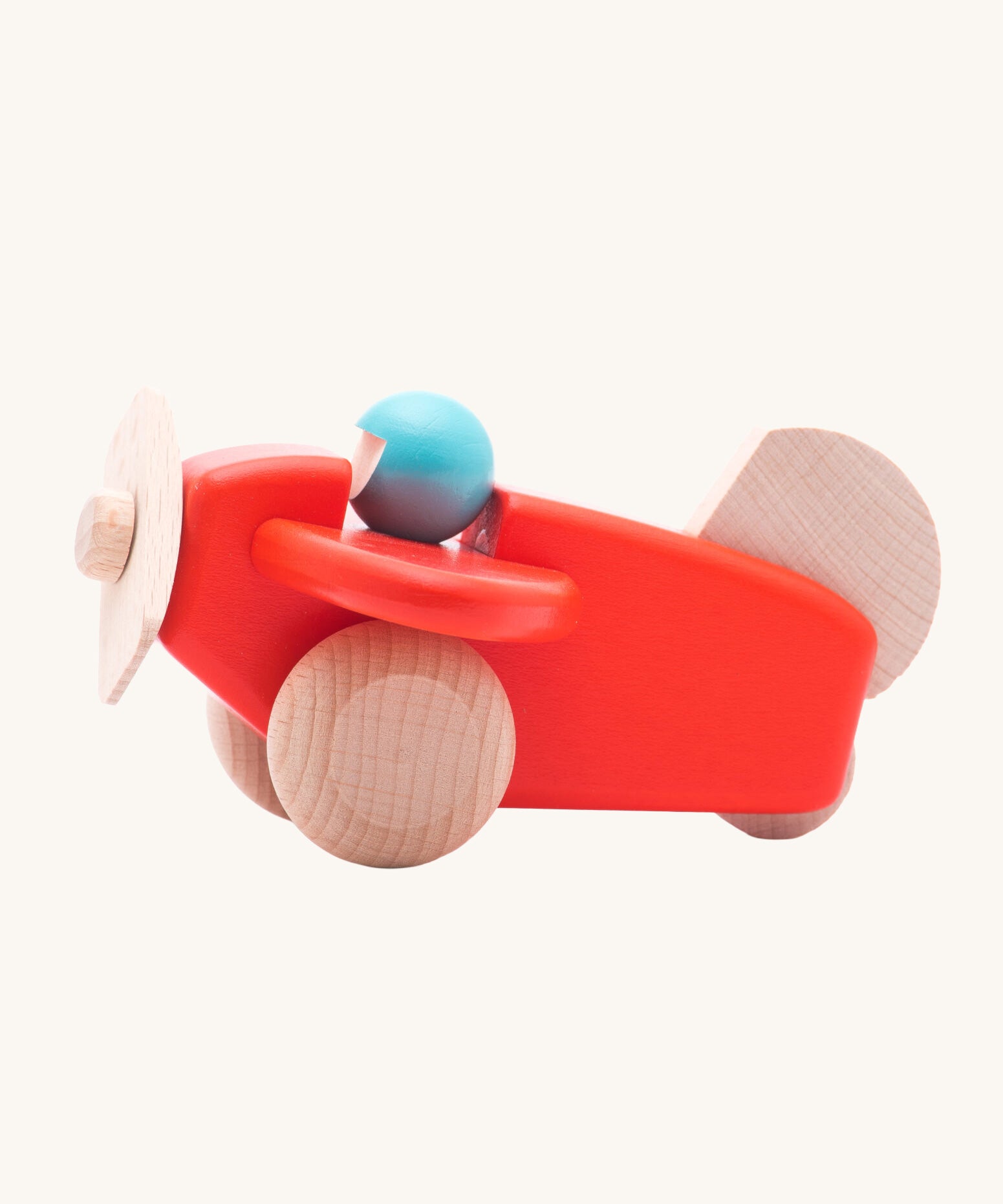 A Bajo coral wooden plane toy with pilot. The coral red coloured plane has natural wheels, propeller and tail and a blue coloured pilot. This plane is part of a wide range of Bajo wooden toy vehicles available at Babipur.