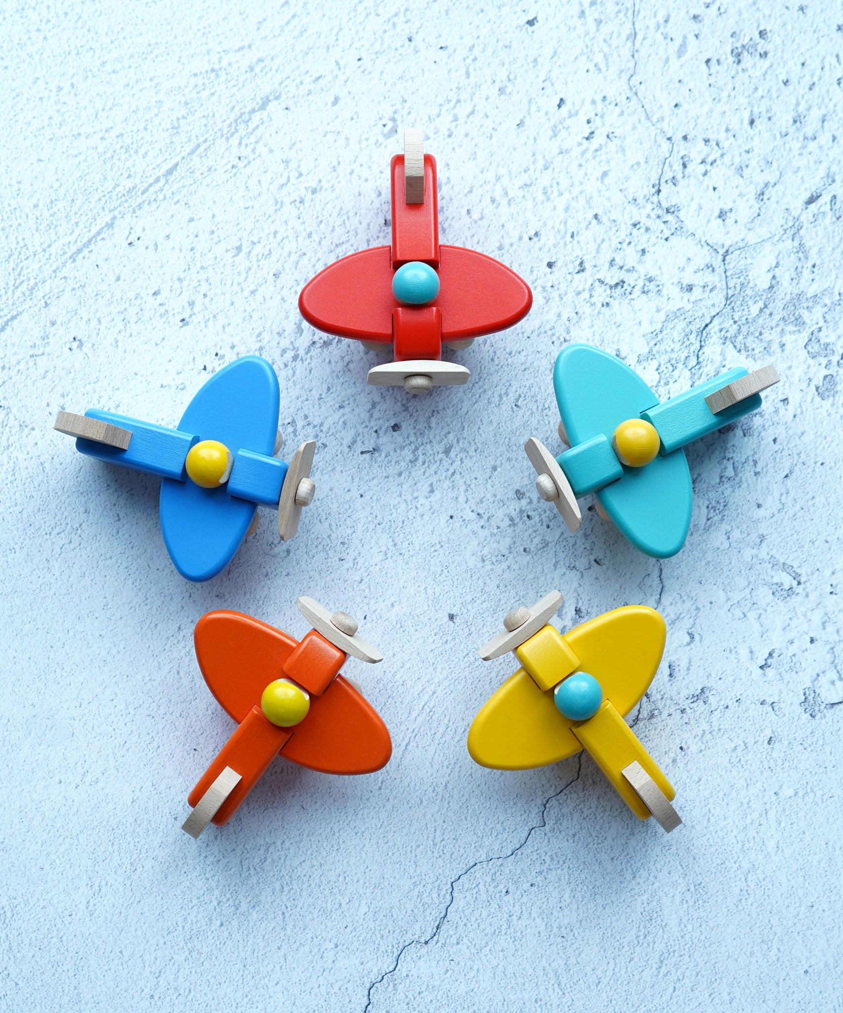 Five Bajo toy planes with pilots placed in a circled pictured from above. These planes is part of a wide range of Bajo wooden toy vehicles available at Babipur.