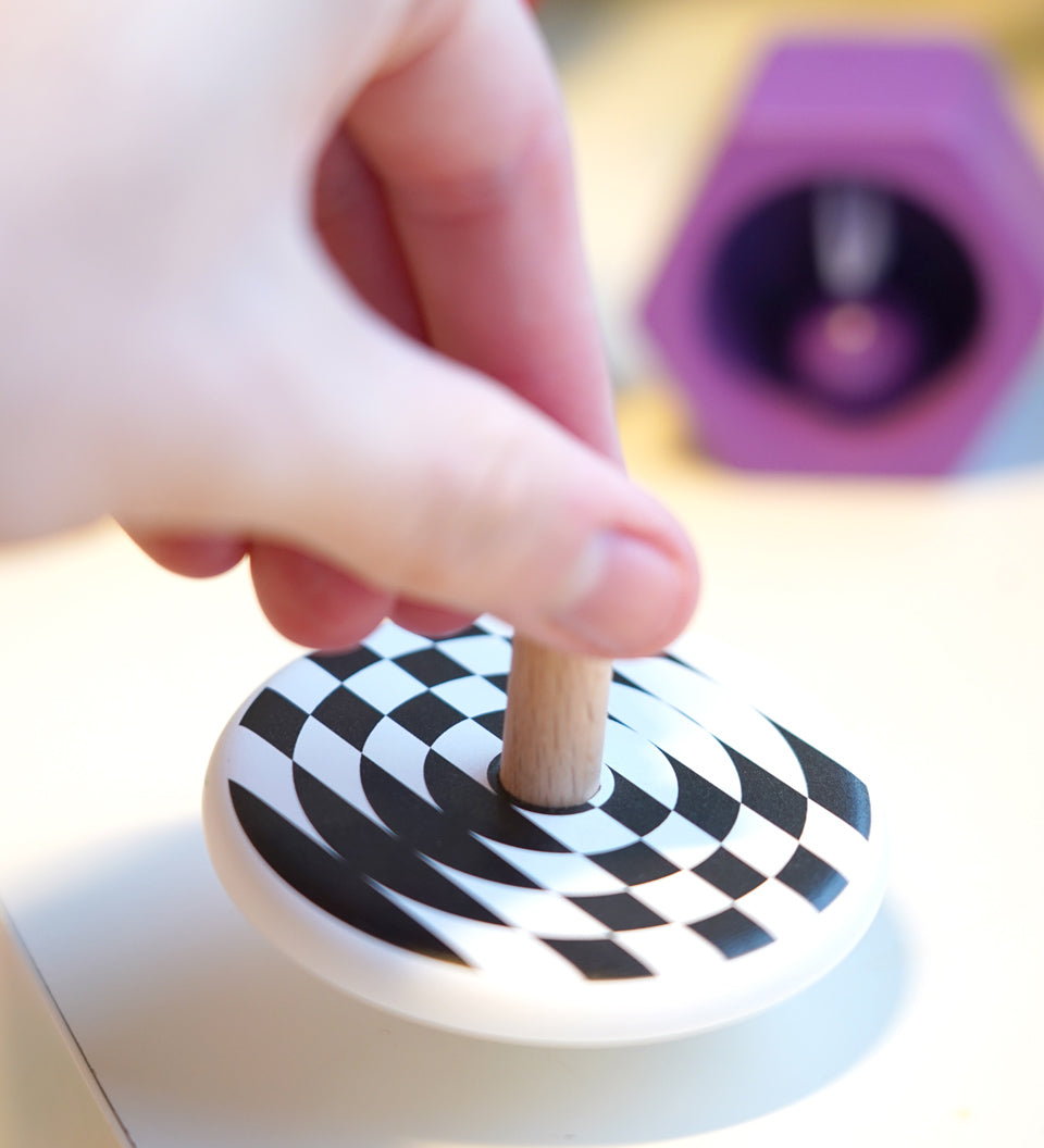 Close up of a hand spinning the Bajo children's wooden latern spinning top