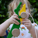 Bajo pull along crocodile wooden toy in a young child's hand.