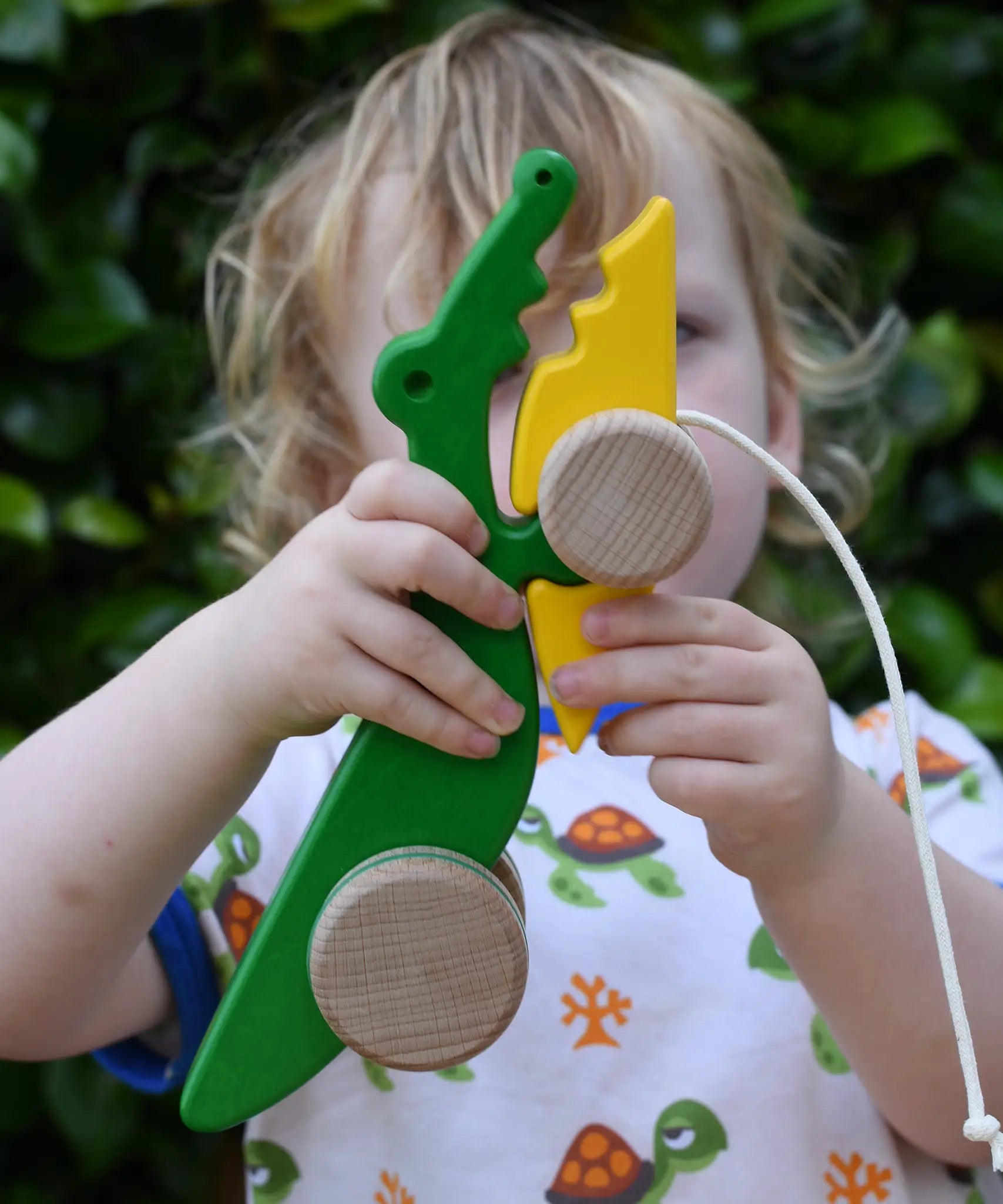 Bajo pull along crocodile wooden toy in a young child's hand.