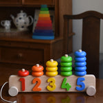 A Bajo 1-5 Pull Along Stacker on a wooden table. A Grimm's Wankel stacking toy can be seen in the background. 