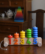 A Bajo 1-5 Pull Along Stacker on a wooden table. A Grimm's Wankel stacking toy can be seen in the background. 