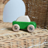 A green coloured Bajo pull back action toy wooden car placed on a child's wicker chair. These heirloom quality toys by Bajo are part of a wide range of wooden toys available here at Babipur. 