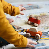 A close up of a child playing with the Bajo pull back action wooden toy cars. The cars have been placed on the road printed on the Wonderie building site cloth. A child playing with the Bajo racing cars that have been placed on a Wonderie building site play cloth. These heirloom quality toys by Bajo are part of a wide range of wooden toys available here at Babipur. 