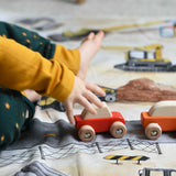 A close up of a child playing with the Bajo pull back action wooden toy cars. The cars have been placed on the road printed on the Wonderie building site cloth. A child playing with the Bajo racing cars that have been placed on a Wonderie building site play cloth. These heirloom quality toys by Bajo are part of a wide range of wooden toys available here at Babipur. 