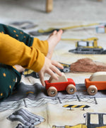 A close up of a child playing with the Bajo pull back action wooden toy cars. The cars have been placed on the road printed on the Wonderie building site cloth. A child playing with the Bajo racing cars that have been placed on a Wonderie building site play cloth. These heirloom quality toys by Bajo are part of a wide range of wooden toys available here at Babipur. 