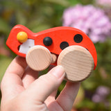 Bajo pull-back ladybird wooden toy figure in an adult's hand.