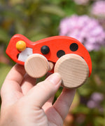 Bajo pull-back ladybird wooden toy figure in an adult's hand.