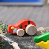 Bajo pull-back ladybird wooden toy placed on a stone wall.