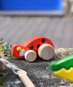 Bajo pull-back ladybird wooden toy placed on a stone wall.