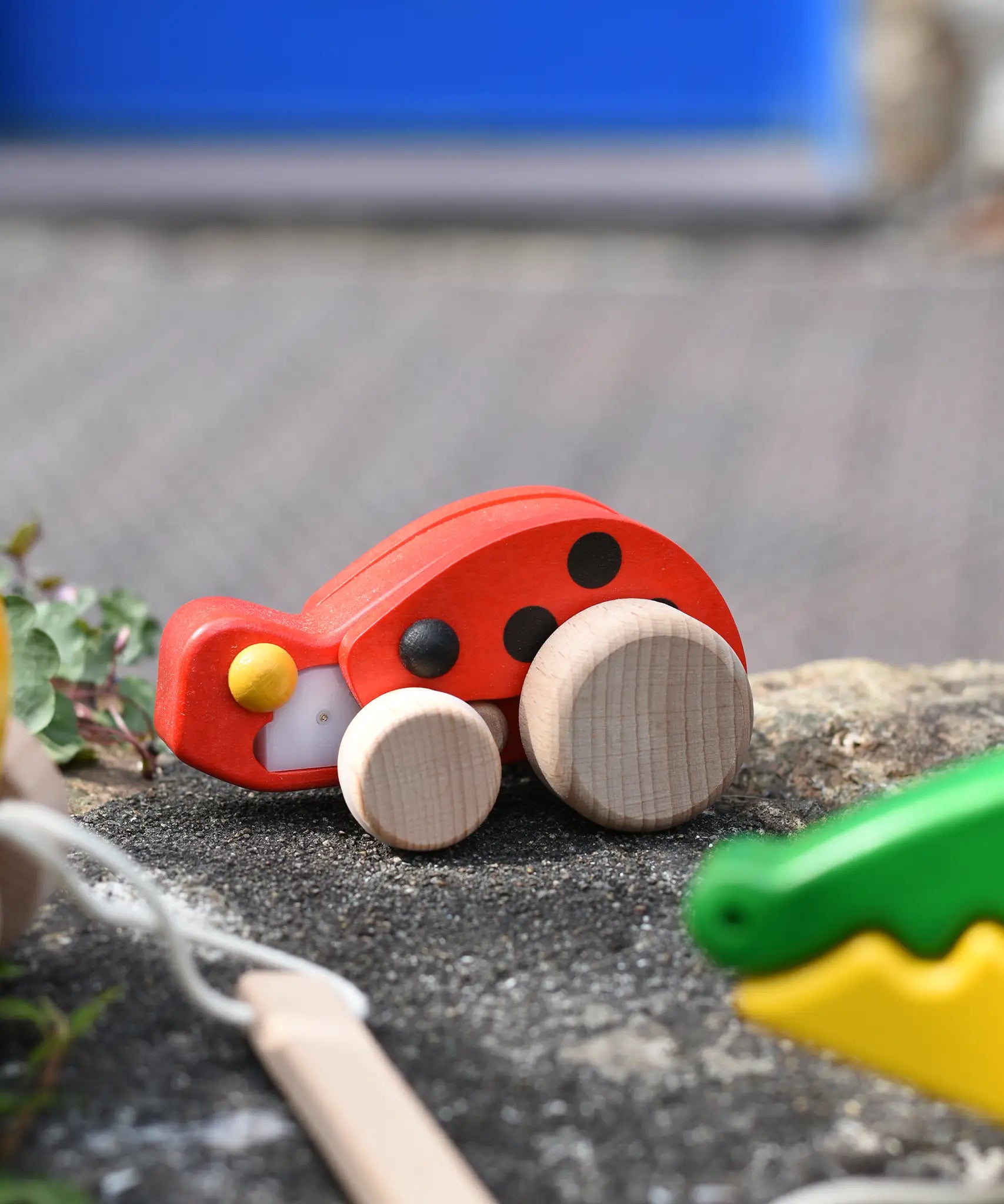 Bajo pull-back ladybird wooden toy placed on a stone wall.