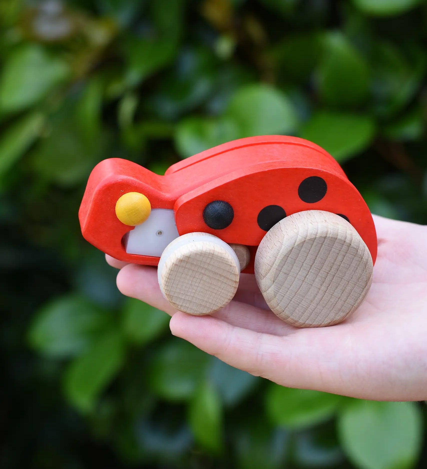 Bajo pull-back ladybird wooden toy figure in a child's hand.