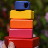 Bajo pyramid sorting board and stacker toy assembled on the base pole piece and shown in an adult's hand.