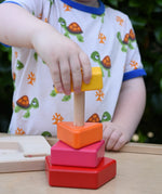 Child playing with the Bajo pyramid sorting board and stacker toy placing a yellow rectangle piece on the stacking pole. 