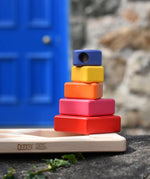 Bajo pyramid sorting board and stacker toy placed on a stone wall with the stacking pole with shapes on placed on the board base.