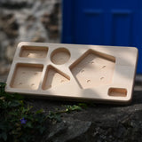 Board base from the Bajo pyramid sorting board and stacker toy placed on a stone wall.