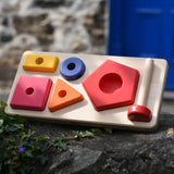 Bajo pyramid sorting board and stacker toy placed on a stone wall.