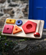 Bajo pyramid sorting board and stacker toy placed on a stone wall.
