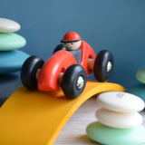 A red Bajo LR car placed on a yellow wooden arch. The car is a part of a wide range of Bajo wooden toy vehicles available at Babipur.