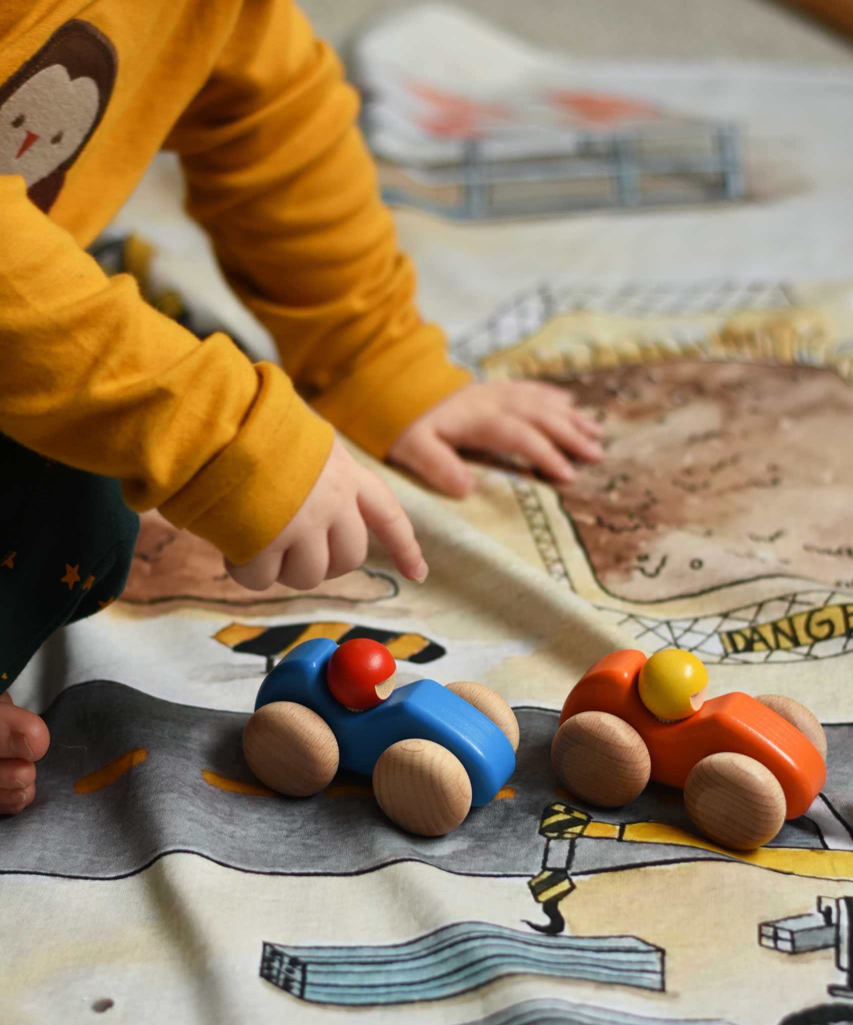 A child playing with the Bajo racing cars that have been placed on a Wonderie building site play cloth. These heirloom quality toys by Bajo are part of a wide range of wooden toys available here at Babipur. 