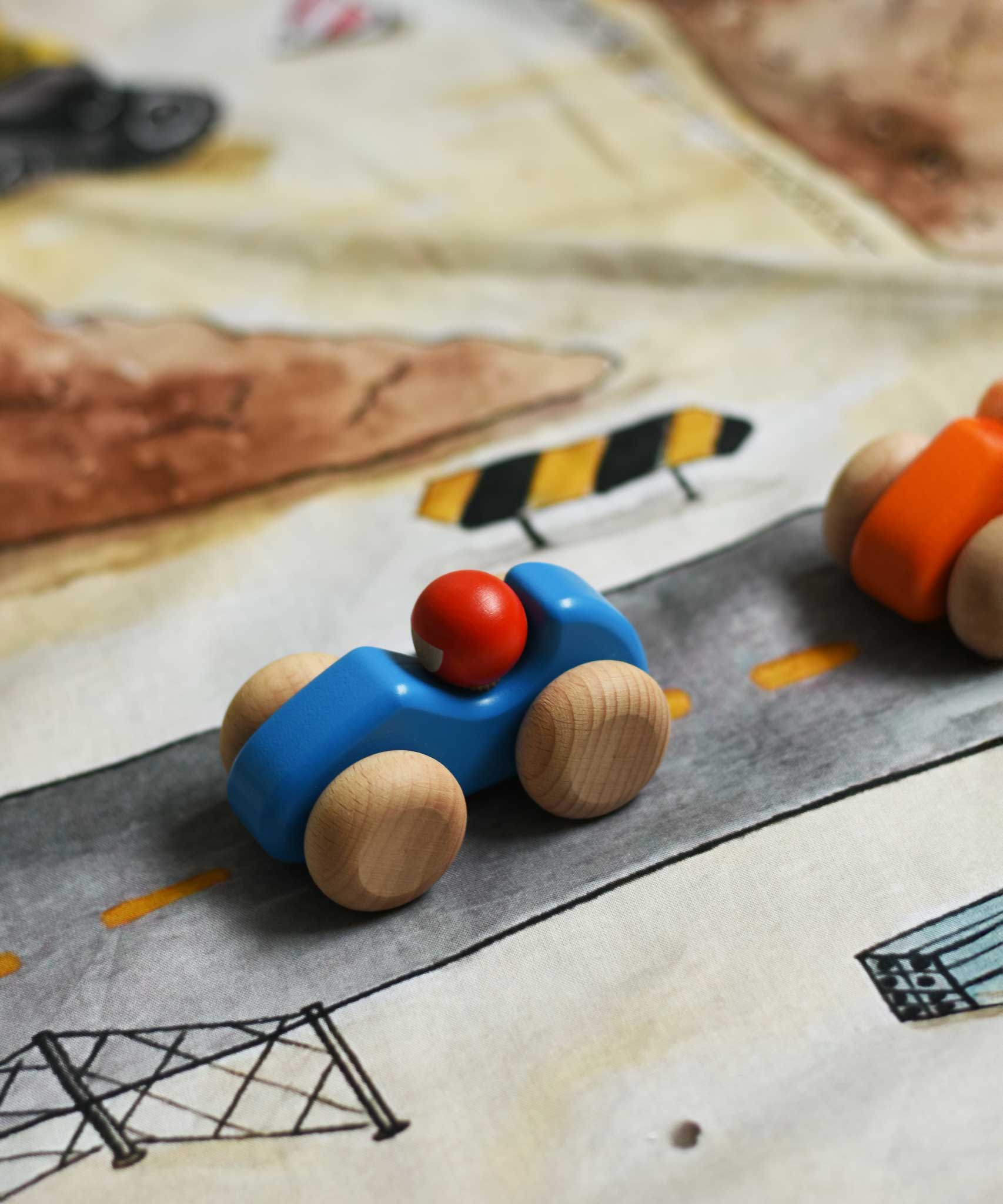 A blue Bajo racing cars  placed on a Wonderie building site play cloth. These heirloom quality toys by Bajo are part of a wide range of wooden toys available here at Babipur. 