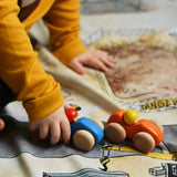 A child playing with the Bajo racing cars that have been placed on a Wonderie building site play cloth. These heirloom quality toys by Bajo are part of a wide range of wooden toys available here at Babipur. 