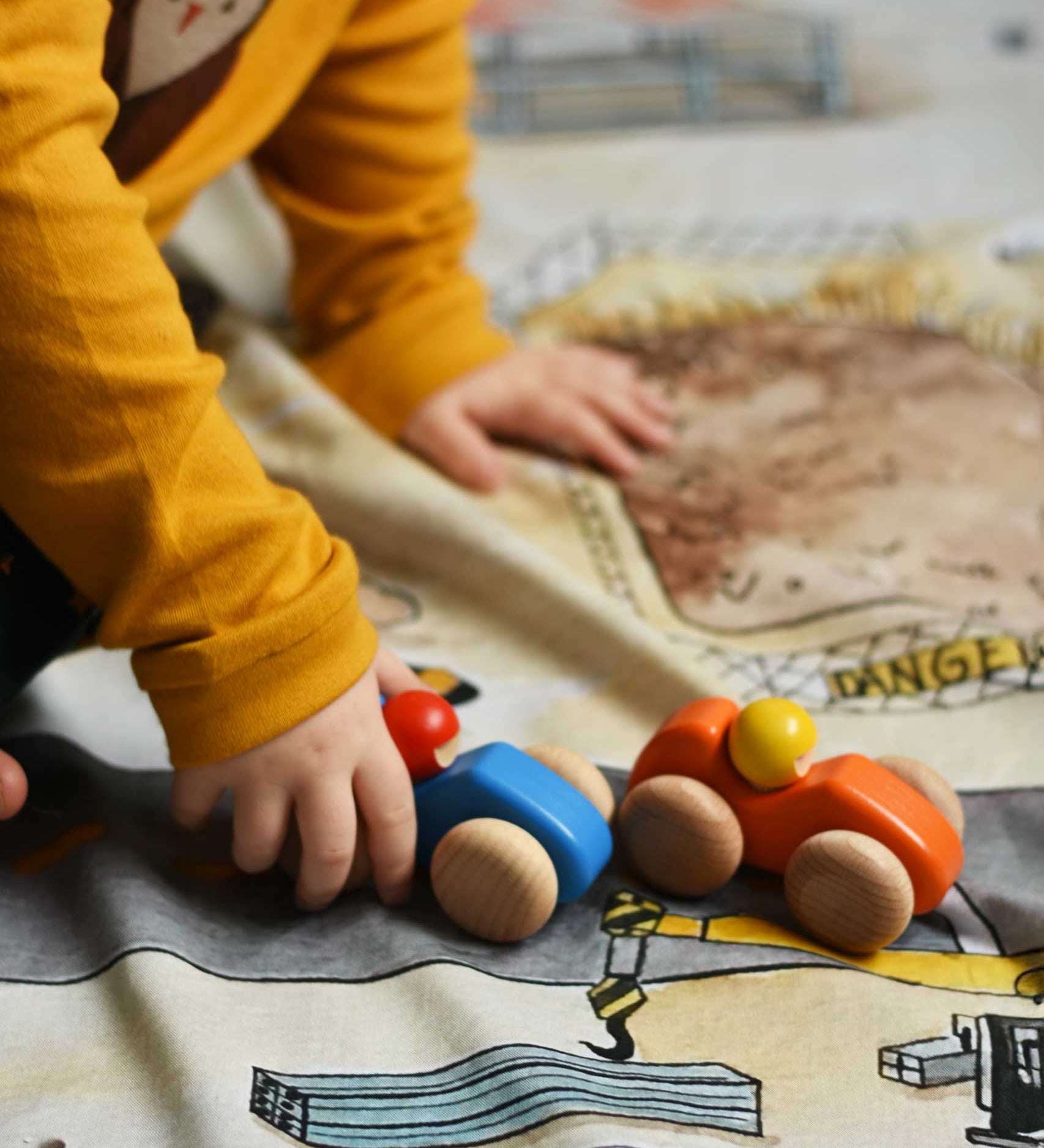 A child playing with the Bajo racing cars that have been placed on a Wonderie building site play cloth. These heirloom quality toys by Bajo are part of a wide range of wooden toys available here at Babipur. 