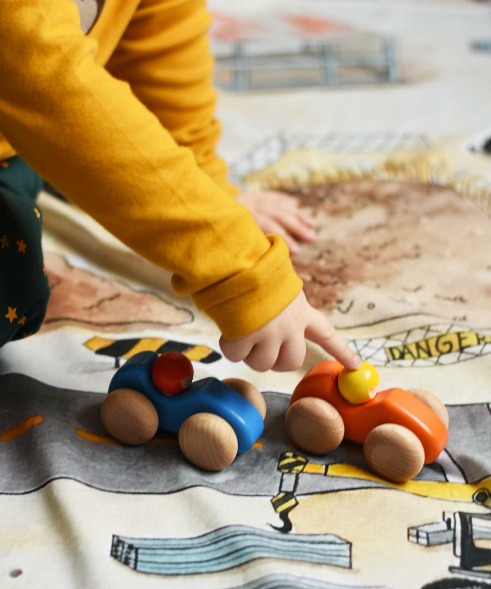 A child playing with the Bajo racing cars that have been placed on a Wonderie building site play cloth. These heirloom quality toys by Bajo are part of a wide range of wooden toys available here at Babipur. 