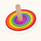Bajo Rainbow Spinning Top. A white painted body with a rainbow design on the top and a natural wooden handle.