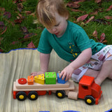 Child playing Bajo large red cargo truck and wooden shape sorter toy outdoors. 