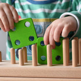 Close up of child placing green square shapes on the back of the Bajo large red cargo truck and wooden shape sorter toy.