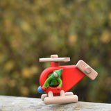 A Kraul passenger felt doll placed in on the Bajo Red Fire Engine Helicopter wooden toy. The red coloured wooden helicopter has natural propellers and stand and a blue lamp details on the front. These heirloom quality toys by Bajo are part of a wide range of wooden toys available here at Babipur. 