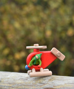A Kraul passenger felt doll placed in on the Bajo Red Fire Engine Helicopter wooden toy. The red coloured wooden helicopter has natural propellers and stand and a blue lamp details on the front. These heirloom quality toys by Bajo are part of a wide range of wooden toys available here at Babipur. 