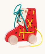 Bajo red Lacing Shoe wooden toy. A red boot shaped threading toy with wheels. These heirloom quality toys by Bajo are part of a wide range of wooden toys available here at Babipur. 