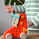 Bajo red lacing shoe wooden push along toy placed on a rattan stool in the Babipur playroom.