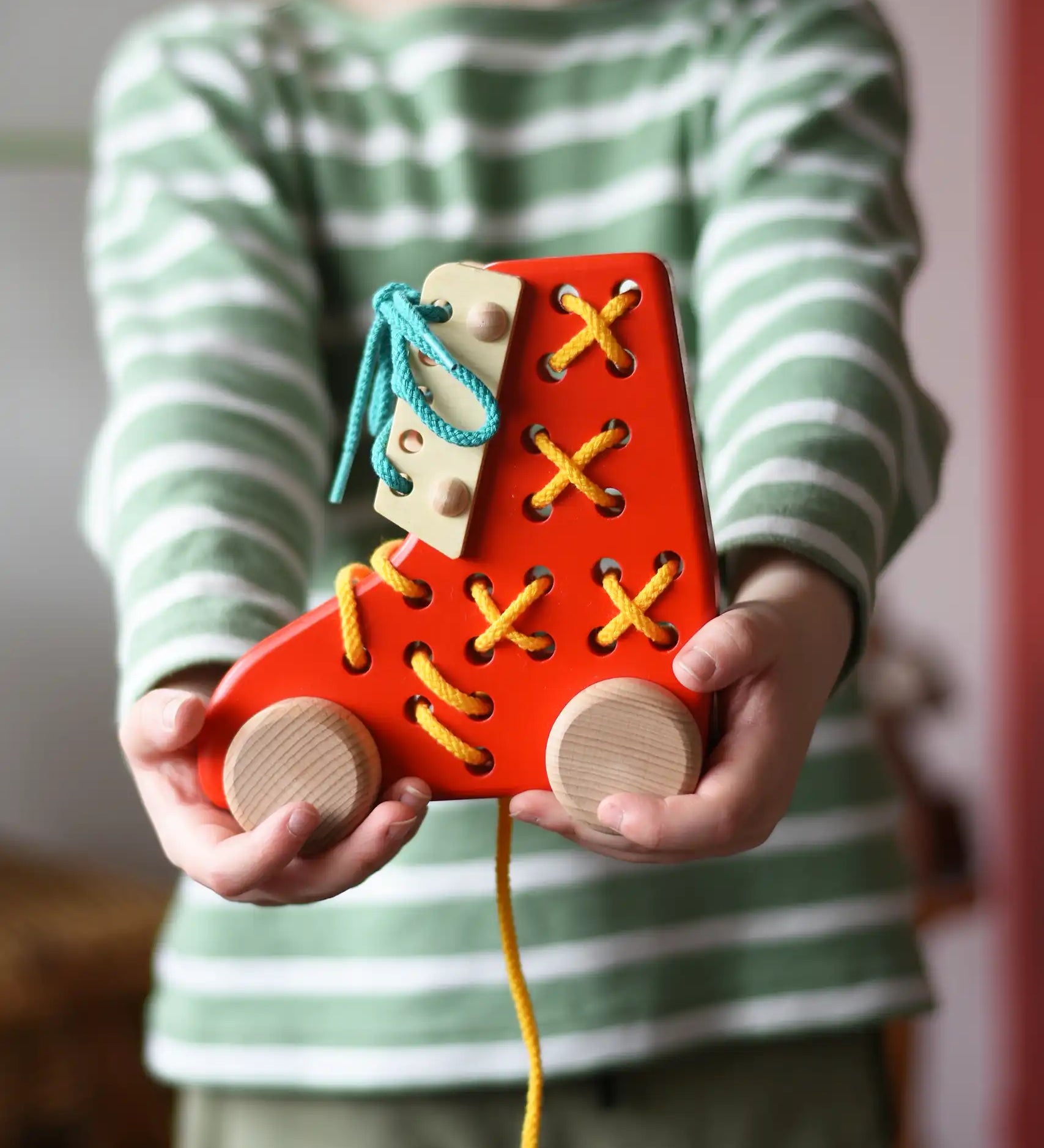 Bajo red lacing shoe wooden push along toy in a child's hands