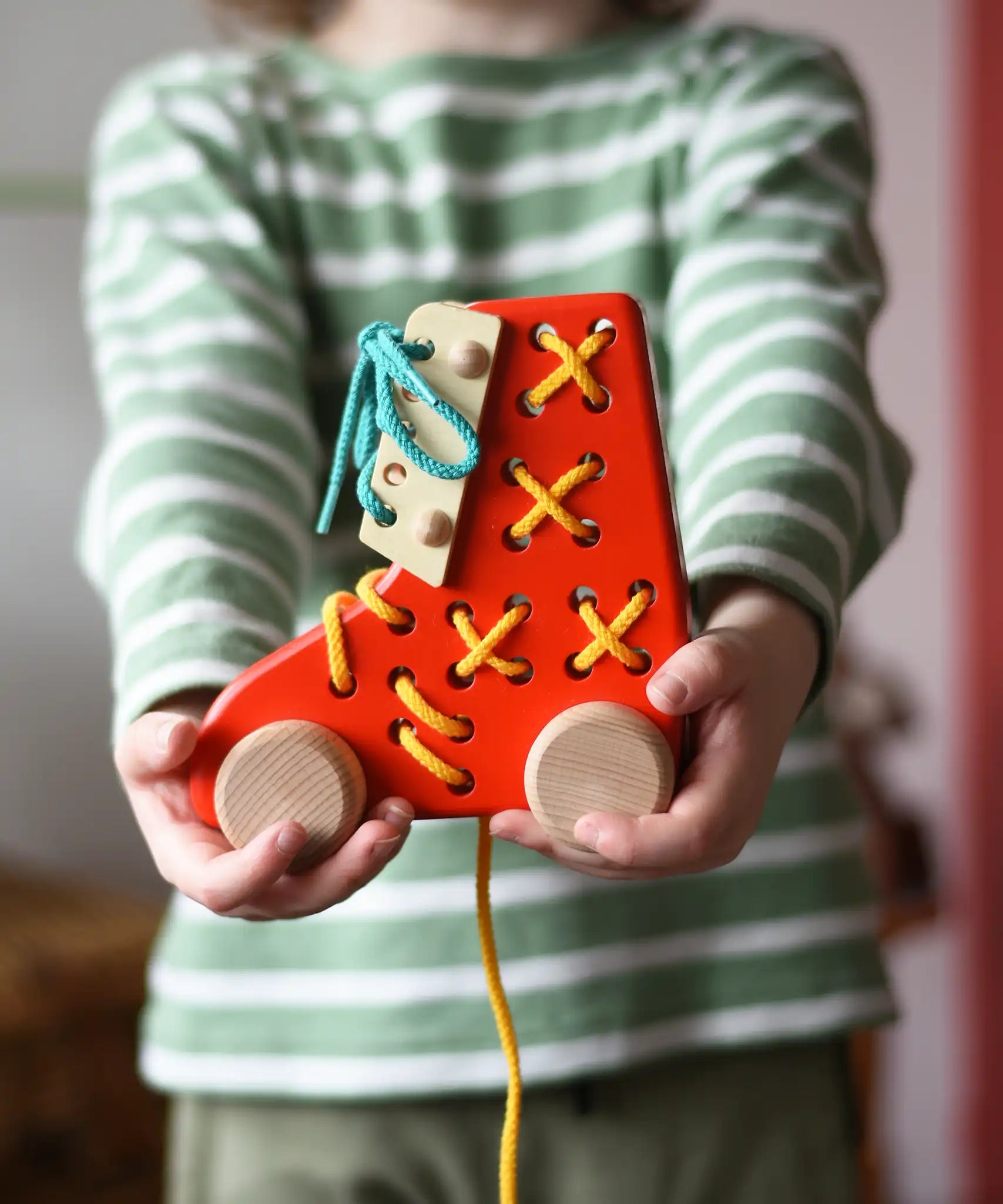 Bajo red lacing shoe wooden push along toy in a child's hands